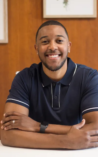 Homem sorrindo, sentado a uma mesa.