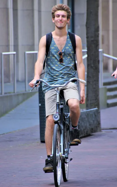 Homem de mochila atravessando a cidade de bicicleta.