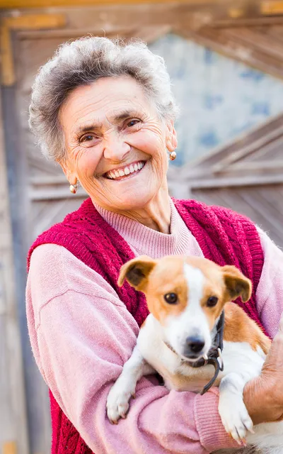 Senhora rindo, com um cachorrinho no colo.