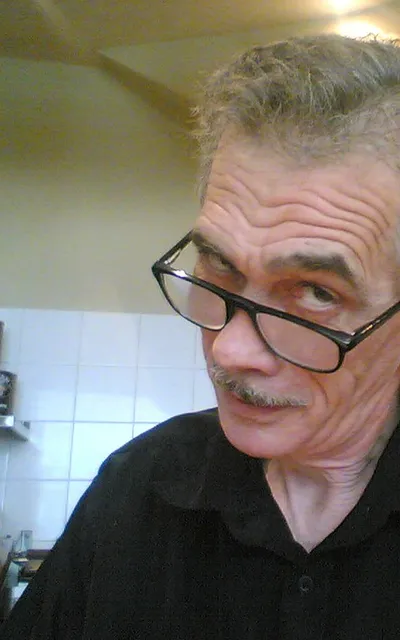 Homem de óculos atrás do balcão de uma cafeteria.