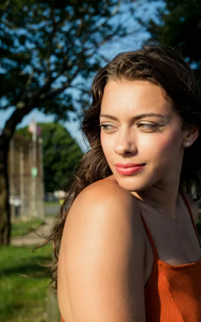 Mulher sorrindo ao ar livre, num dia de sol.